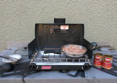 Cooking over a propane camp stove. It'll get the job done, but the novelty wears off after a while.