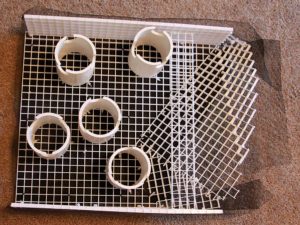 The underside of the false bottom reveals sections of PVC pipe used as support legs. Note the notches cut in the bottoms; this allows water to flow down, through, and out of the pipes.